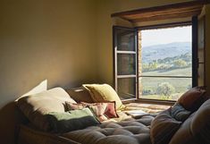 a bed sitting in front of a window with pillows on it's headboard