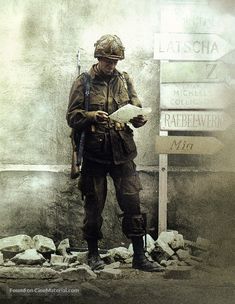 a man in uniform standing next to a sign and holding a piece of paper with writing on it