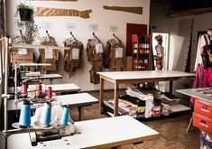 a sewing studio with lots of crafting supplies on the walls and tables in front of them