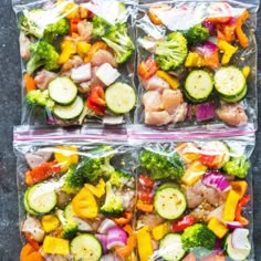 three plastic bags filled with assorted veggies on top of a gray surface