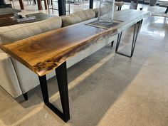 a wooden table sitting in the middle of a living room next to couches and tables