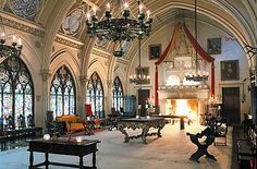 a large room with chandeliers, tables and benches in front of two windows