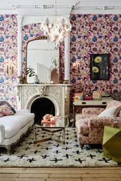 a living room filled with lots of furniture and walls covered in floral wall coverings