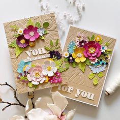 two cards with flowers on them sitting next to each other