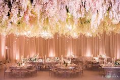 an elegant wedding reception with pink flowers and chandeliers hanging from the ceiling over tables