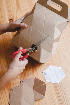 someone cutting up some paper with scissors on a table next to boxes and envelopes