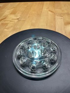 a glass plate sitting on top of a wooden table next to a black object with holes in it