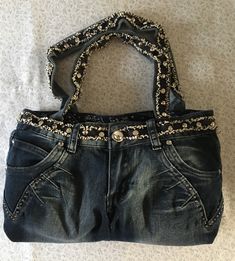 This jean purse is beautifully garnished with silver brades and eye catching glass button. The band and handle straps are covered with dark blue raveled trim with large silver and glass brades. The back pockets are garnished with rows of five star glass gems. The purse is fully lined with western blue handkerchief fabric with two inside pockets. The purse has a Velcro fascine. the size of the purse is 16 inches wide and 9 inches tall. How To Make A Purse Out Of Jeans, Jean Pocket Purse, Purse Aesthetic, Blue Handkerchief, Jean Bag, Jean Purses, Denim Crafts Diy, Bag Jeans, Jean Purse