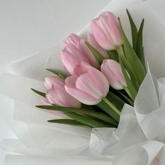 a bouquet of pink tulips sitting on top of white paper