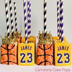 three candles with basketball themed boxes and crowns on them, all decorated in orange and purple