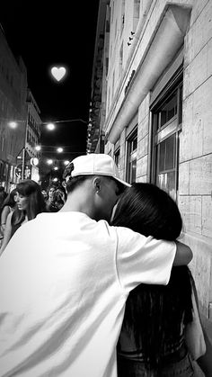 black and white photograph of a man kissing a woman on the side of a building