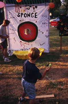 a young boy holding a green frisbee in front of a sign that says sponge