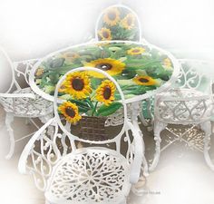 a table with sunflowers painted on the top and white chairs around it,