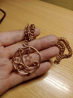 a person is holding a gold necklace with a star and swirl design in the middle