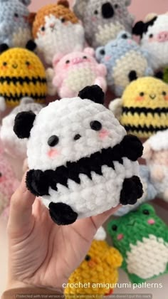 a hand is holding a small crocheted toy in front of many stuffed animals