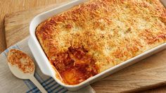 a casserole dish on a wooden cutting board with a spoon