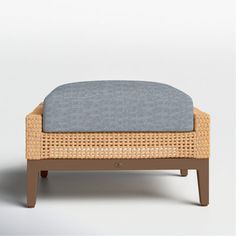 the foot stool is made out of wicker and has a blue cushion on it