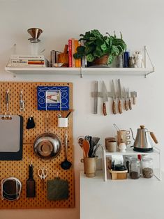 there are many kitchen utensils on the pegboard in this room, including pots and pans