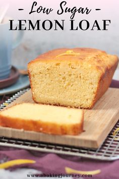 a loaf of lemon bread sitting on top of a wooden cutting board next to a cup and saucer