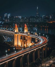 an aerial view of a city at night with lights on and bridges over the water