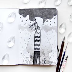 an open notebook with water drops surrounding it and a drawing of a person in the rain