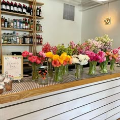 the flowers are lined up on the counter at the flower shop in front of the bar