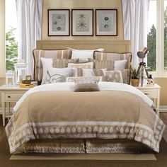 a bed with beige and white comforters in a bedroom next to two pictures on the wall