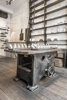 an old fashioned stove sitting on top of a wooden floor next to shelves filled with bottles