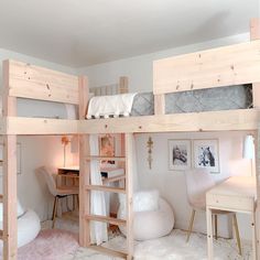 a bedroom with bunk beds and desks in the corner next to a white chair