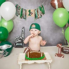 a baby is sitting in front of a football cake