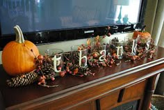 a wooden table topped with lots of pumpkins and other decorations next to a flat screen tv