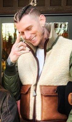 a man with dreadlocks wearing a brown and tan leather jacket is standing in front of a door