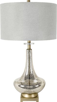 a table lamp with a white shade on top and a gold base, sitting next to a