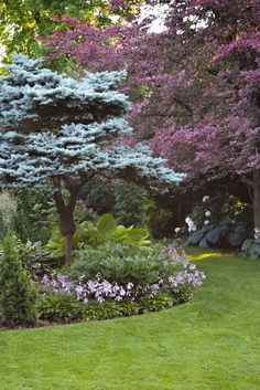 a park bench sitting in the middle of a lush green field next to trees and flowers