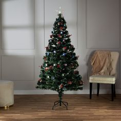 a small christmas tree in a living room with a chair and ottoman on the floor