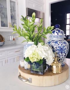 vases and flowers sit on top of a table in the middle of a kitchen