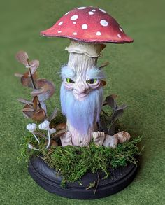 a small mushroom with green eyes sitting on top of a potted plant in the grass