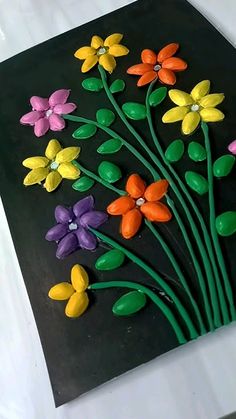 there are many colorful flowers on the black paper with green stems and yellow, pink, orange, and purple flowers