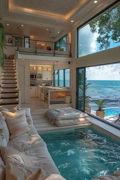 a living room filled with furniture next to an indoor swimming pool and ocean view window