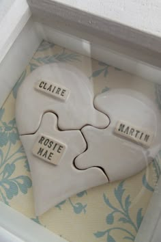 two white heart shaped pieces with words on them in a box that says claire, rose, mae and martin