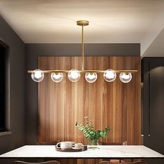 a modern kitchen with marble counter tops and wooden paneling, along with hanging lights over the island