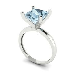 a white gold ring with an aqua blue topazte stone in the center, on a white background