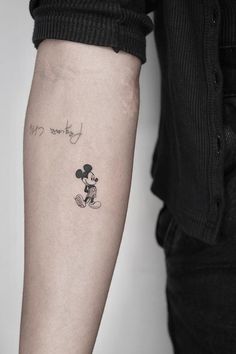 a person with a mickey mouse tattoo on their left arm and the word love is written in black ink