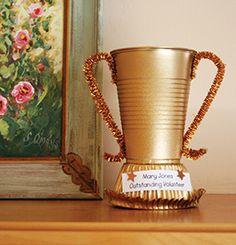 a gold trophy sitting on top of a wooden table next to a painting and framed picture