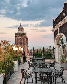 an outdoor dining area with tables, chairs and potted plants on the roof terrace