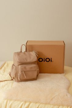 a small backpack sitting on top of a bed next to a box with the word io