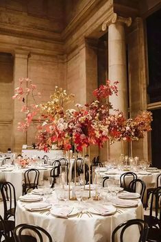 the tables are set with white tablecloths and tall vases filled with flowers