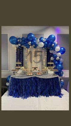 a table topped with blue and white balloons next to a number 15 cake on top of a table