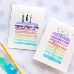 two cards with birthday candles on them next to a paintbrush and watercolor pencil