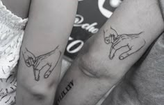 two people holding hands with tattoos on their arms